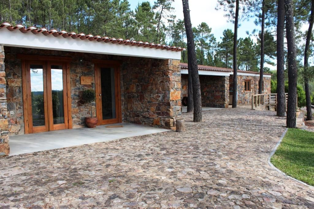 A stone building with a tiled roof, a paved entrance, and a pathway leading to another structure.