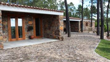 A stone building with a tiled roof, a paved entrance, and a pathway leading to another structure.
