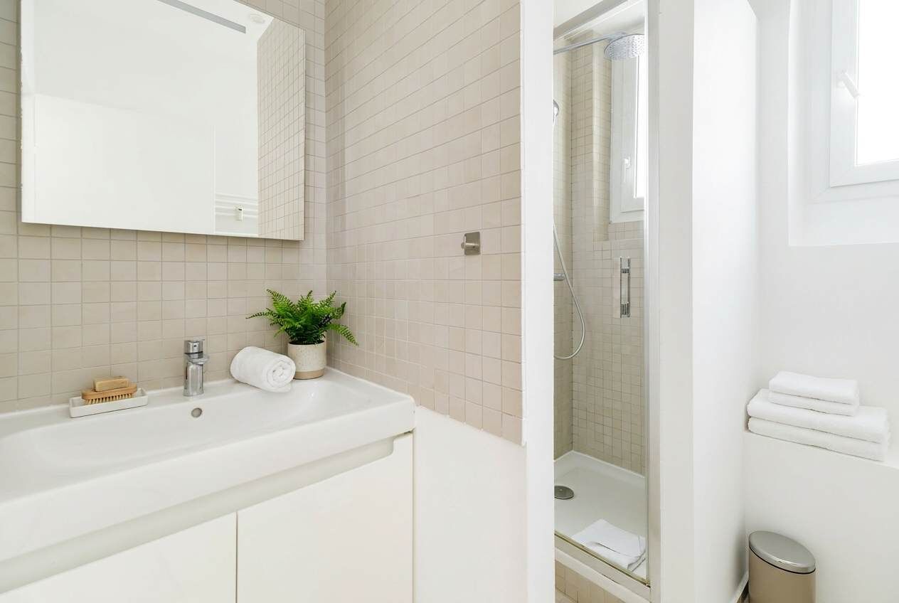 A bathroom with a white sink, mirror, and shower.