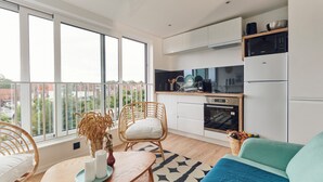 Eine moderne Küche mit einem großen Fenster, einem Essbereich mit Tisch und Stühlen sowie einem Wohnbereich mit einer Couch.