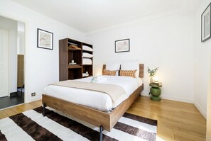 Ein Schlafzimmer mit einem hölzernen Bett, einem großen Kleiderschrank, einer Zimmerpflanze und einem gerahmten Bild an der Wand.