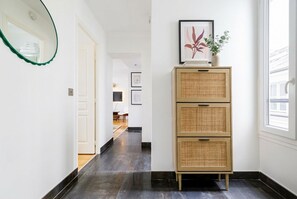 Ein Flur mit einem Spiegel, einem Korbschrank und gerahmten Kunstwerken.