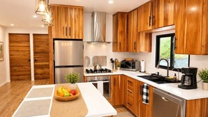 Eine moderne Küche mit Holzschränken, Edelstahlgeräten und einer zentralen Kochinsel mit Obstschale.