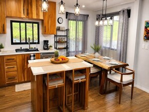 A kitchen with wooden cabinets, a central island, and pendant lighting. - Modern Nature Retreat Between Jungle & Ocean (Savegre)