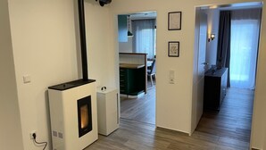 Ett modernt vardagsrum med en vedeldad kamin, en matplats och ett kök.