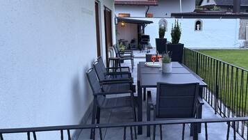 Eine Terrasse mit Tisch und Stühlen, einem Blumentopf und Blick auf ein Haus mit rotem Dach.