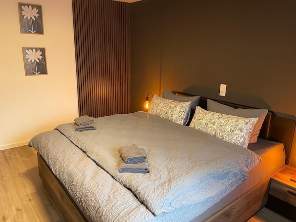 A neatly made bed with a textured blanket, a bedside lamp, and patterned pillows.