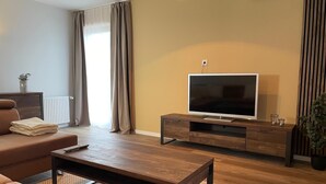 Ett modernt vardagsrum med en soffa, ett soffbord, en tv på ett träställ och ett element.
