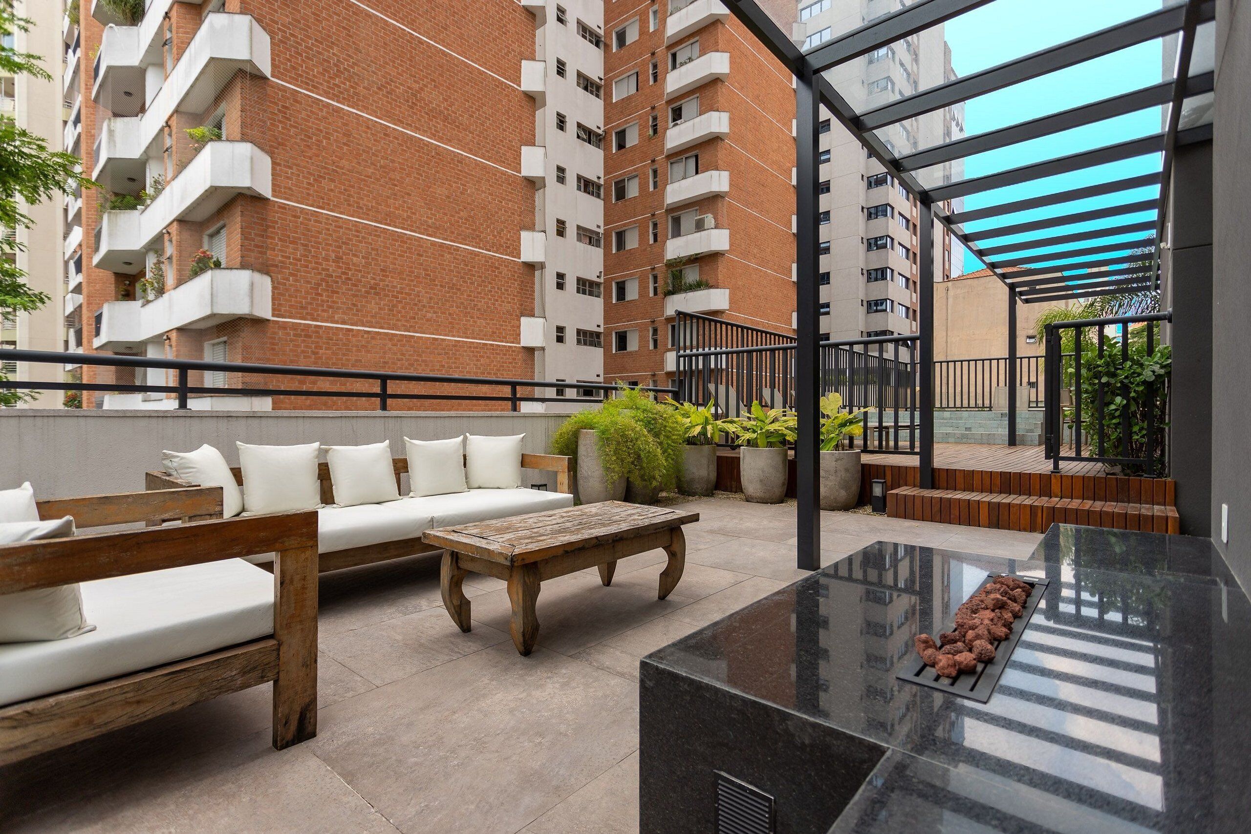 A rooftop patio with outdoor furniture, a grill, and a view of high-rise buildings.