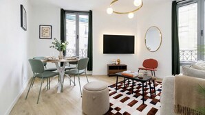 Ein modernes Wohnzimmer mit Essbereich, einem Flachbildfernseher und einem großen Fenster.