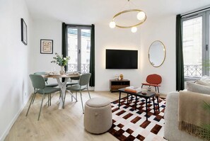 Ein modernes Wohnzimmer mit Essbereich, einem Flachbildfernseher und einem großen Fenster.