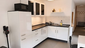 Une cuisine moderne avec des meubles blancs, un plan de travail noir, un four à micro-ondes et un évier.