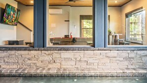 Een modern interieur met een stenen muur, een zwembad en uitzicht op een keuken en een eetgedeelte.