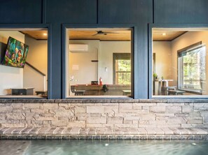 Ein modernes Interieur mit Steinwand, Pool und Blick auf Küchen- und Essbereich.