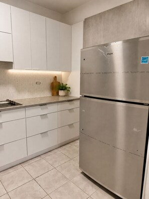 A modern kitchen with white cabinetry, a stainless steel refrigerator, and a tiled floor. - Casa Cecilia Retreat w/pool Near PR’s Best Beaches (Aguada)