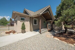 A two-story house with a sloped roof, a front porch, and a small front yard with a tree and a potted plant. - Brand New Cozy Getaway - Mountain Views + Firepit (Buena Vista)