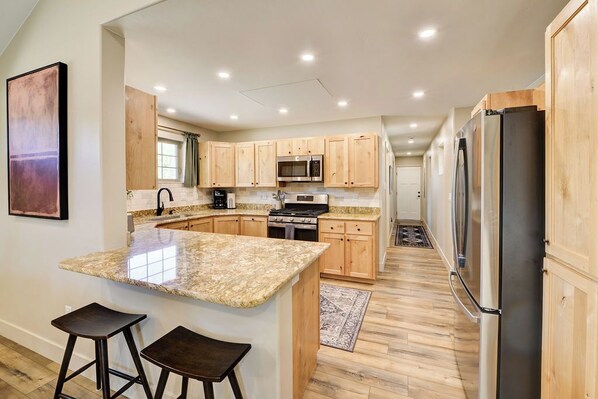 A modern kitchen with granite countertops, wooden cabinets, and stainless steel appliances. - Brand New Cozy Getaway - Mountain Views + Firepit (Buena Vista)