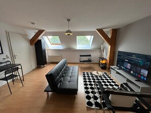 A modern living room with a sofa, a dining table, a TV, and a black and white patterned rug. - Apartment "City Loft at Schillerpark" with Wi-Fi (Dessau-Roßlau)