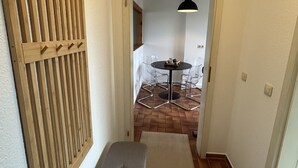 Ein Flur mit einer Wand aus Holzleisten, einer Bank und einem Essbereich mit Tisch und Stühlen.