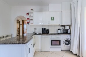 A compact kitchen with white cabinets, a built-in oven, microwave, and dishwasher. - #397 Comfortable Apartment by the Beach (Albufeira)
