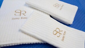 Two white towels with embroidered logos on a blue textured surface.