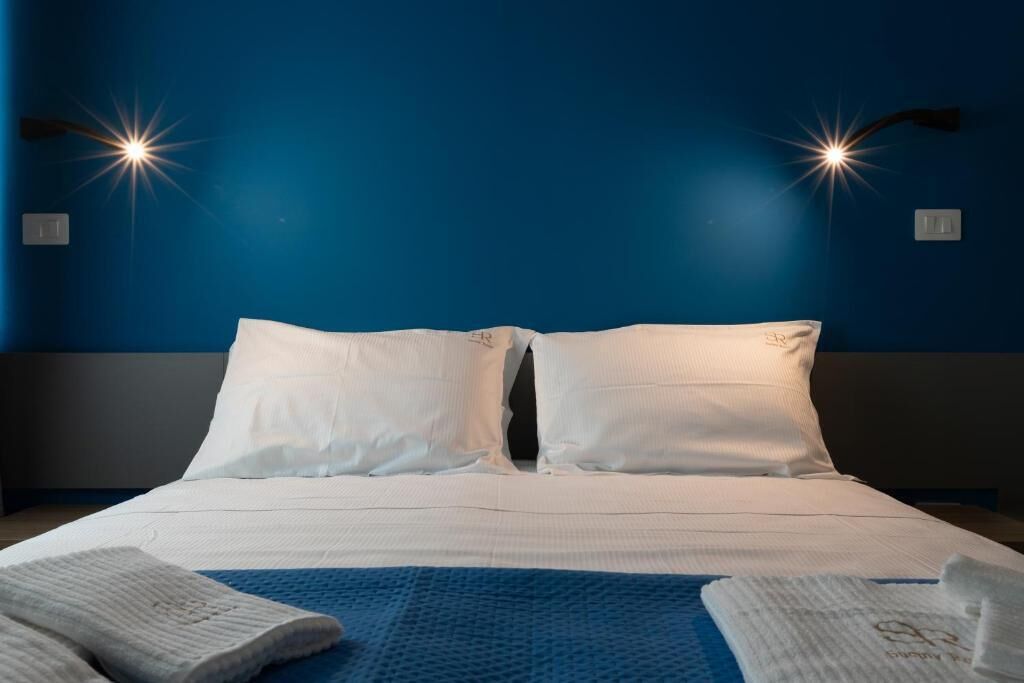 Ein Hotelzimmer mit Bett, zwei Kissen, einer blauen Decke und zwei Handtüchern.