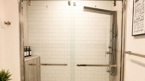 A bathroom with a glass-enclosed shower, a toilet, and a small rug. - The Dallas Gem Tranquil 1-bedroom apartment with AC in vibrant Dallas (Dallas)