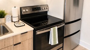 A modern kitchen with stainless steel appliances, a black stove, and wooden cabinets. - The Dallas Gem Tranquil 1-bedroom apartment with AC in vibrant Dallas (Dallas)