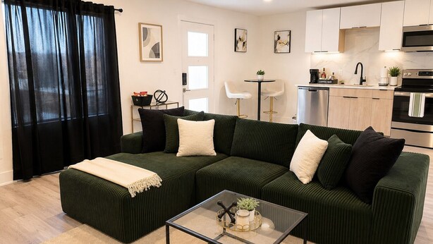 A modern living room with a green sofa, a glass coffee table, and a kitchen in the background. - The Dallas Gem Tranquil 1-bedroom apartment with AC in vibrant Dallas (Dallas)