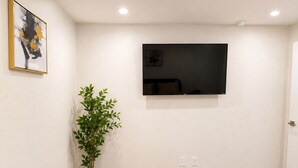A bedroom with a bed, a potted plant, a flat-screen TV mounted on the wall, and a door. - The Dallas Gem Tranquil 1-bedroom apartment with AC in vibrant Dallas (Dallas)