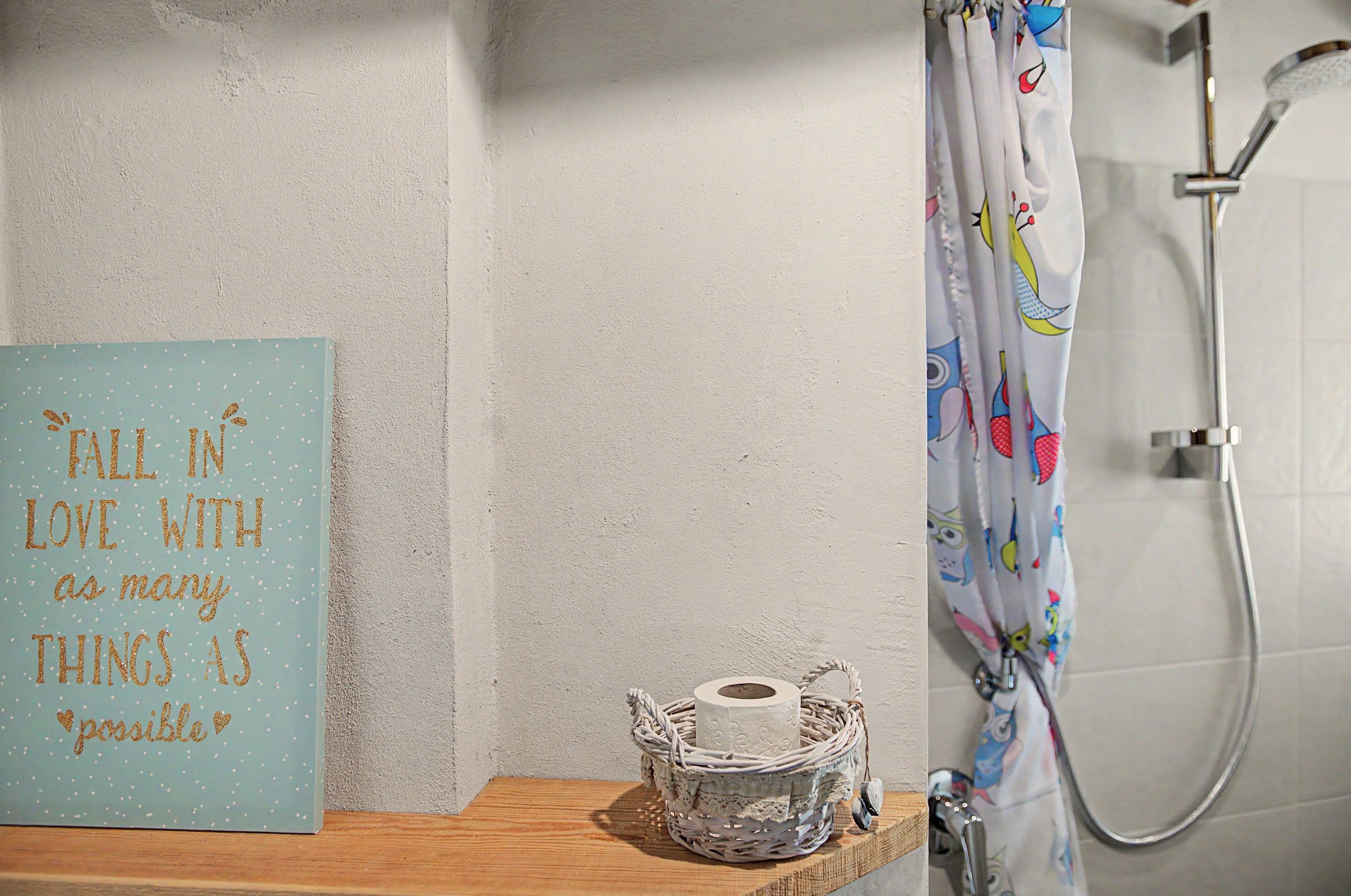 Un bagno con tenda da doccia, un rotolo di carta igienica e un cartello con una citazione motivazionale.