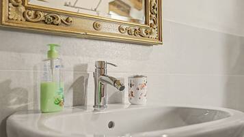 Un lavandino da bagno con uno specchio sopra, un dispenser di sapone e una tazza decorata con un motivo canino.