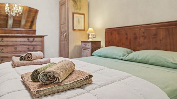 Un lit bien fait, avec des serviettes pliées et une tête de lit en bois.