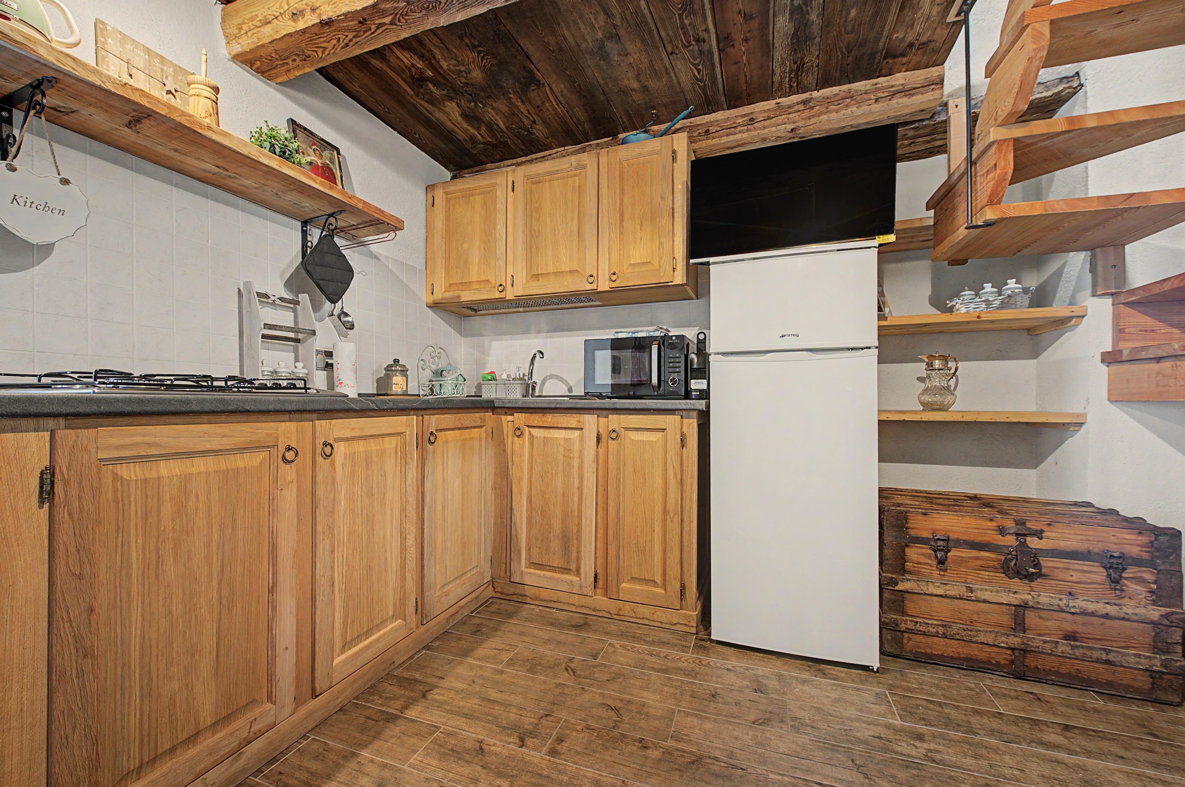 Une cuisine avec des meubles de rangement en bois, un réfrigérateur blanc, un four à micro-ondes et une cuisinière.