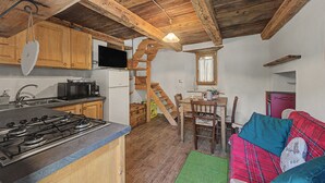 A compact kitchen with wooden cabinets, a gas stove, a microwave, and a refrigerator.