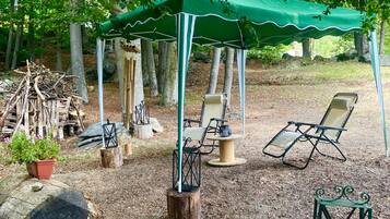 Un espace extérieur aménagé avec des sièges, un auvent verdoyant, des chaises en bois et une table.