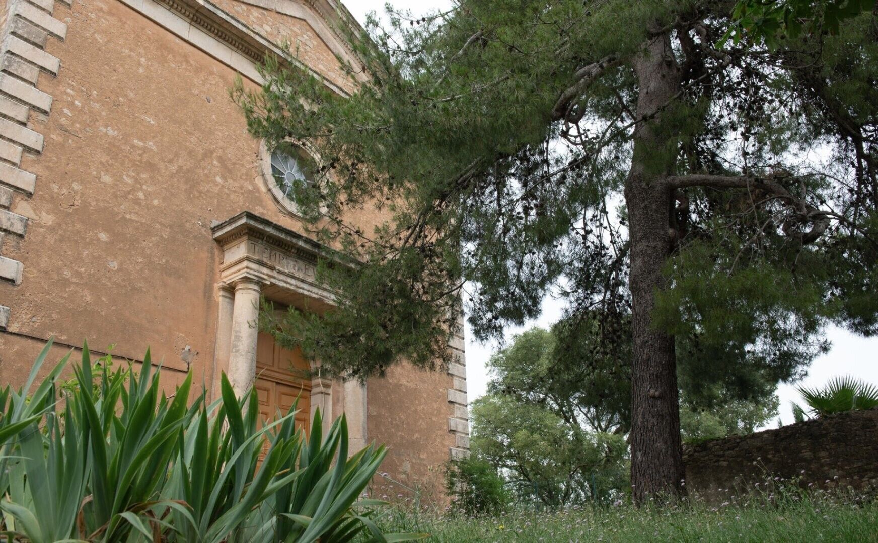 Un bâtiment de style architectural classique, caractérisé par une entrée imposante avec des colonnes et une fenêtre circulaire.