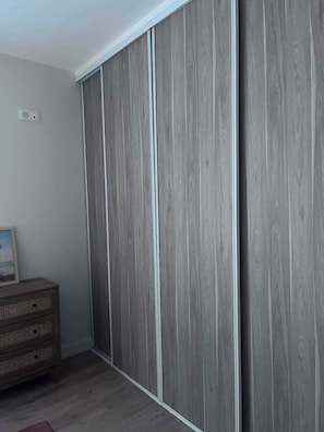 A room with a wardrobe, a dresser, and a framed picture on the wall.