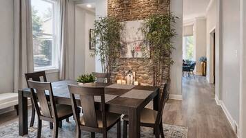 A dining area with a stone accent wall, a table with chairs, and a patterned rug.