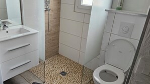 Ett badrum med handfat, spegel, dusch, toalett och tvättmaskin.