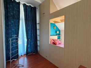 A room with a built-in wardrobe, a window with a view of another room, and a wooden floor. - Vacation Rental in the Brocéliande Forest (Néant-sur-Yvel)