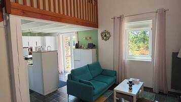 Un espacio de sala con un sofá color turquesa, una mesita y un ventanal con cortinas.