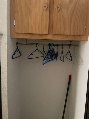 A wooden cabinet with a metal rod and multiple hangers.