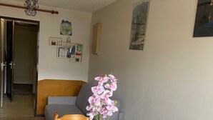 Un coin repas avec une table dressée pour deux personnes, une orchidée en pot et un mur orné de tableaux et d’un panneau d’affichage.