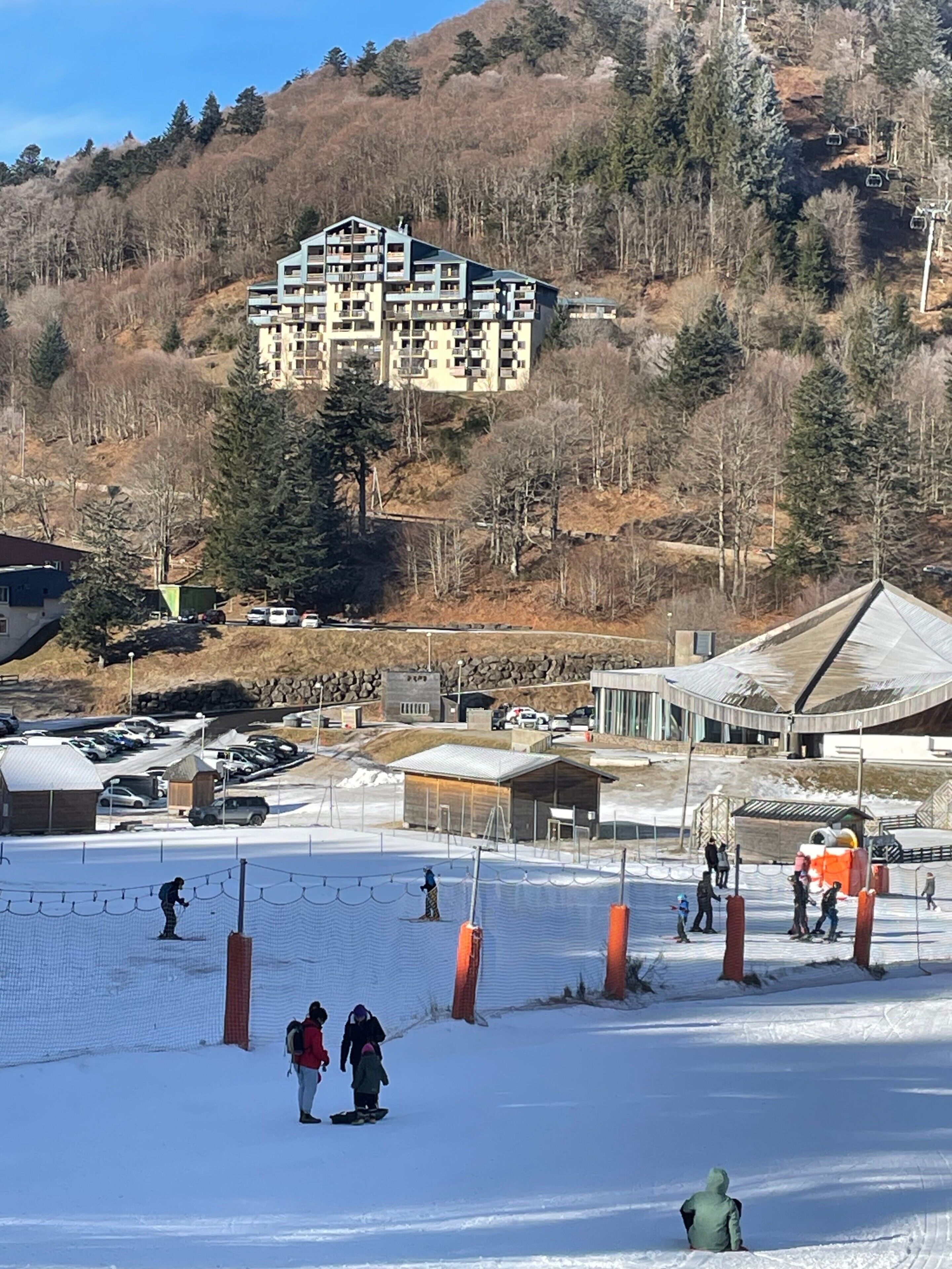 Une station de ski dotée d’un grand bâtiment, de pistes de ski et d’un parking.