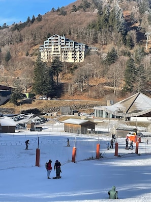 A ski resort with a large building, ski slopes, and a parking area.
