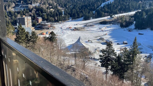 Un paysage montagneux avec une station de ski, des bâtiments et une zone recouverte de neige.