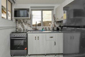 Eine moderne Küche mit Einbau-Mikrowelle, Backofen und Kühlschrank, Marmor-Spritzschutz und einem Fenster mit Blick.