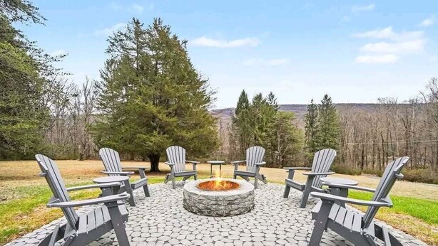 A fire pit surrounded by Adirondack chairs on a stone patio with a view of trees and hills. - Family Retreat, Hunting Lodge, or adventure base camp - The choice is yours (Blain)