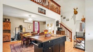 A spacious kitchen with a central island, wooden flooring, a staircase, and a mounted deer head. - Family Retreat, Hunting Lodge, or adventure base camp - The choice is yours (Blain)